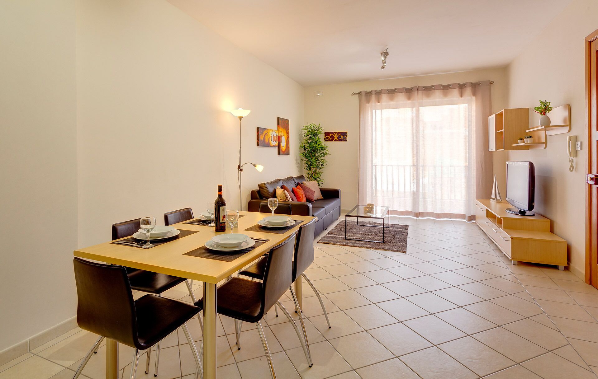 Un soggiorno moderno con zona pranzo. Si vede un divano, una TV e un tavolo da pranzo con sedie.