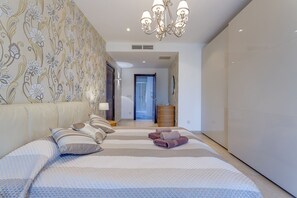 A modern bedroom with a large bed, a chandelier, and a patterned wallpaper. - Luxury Seafront Oasis in Central Sliema with Pool (Sliema)