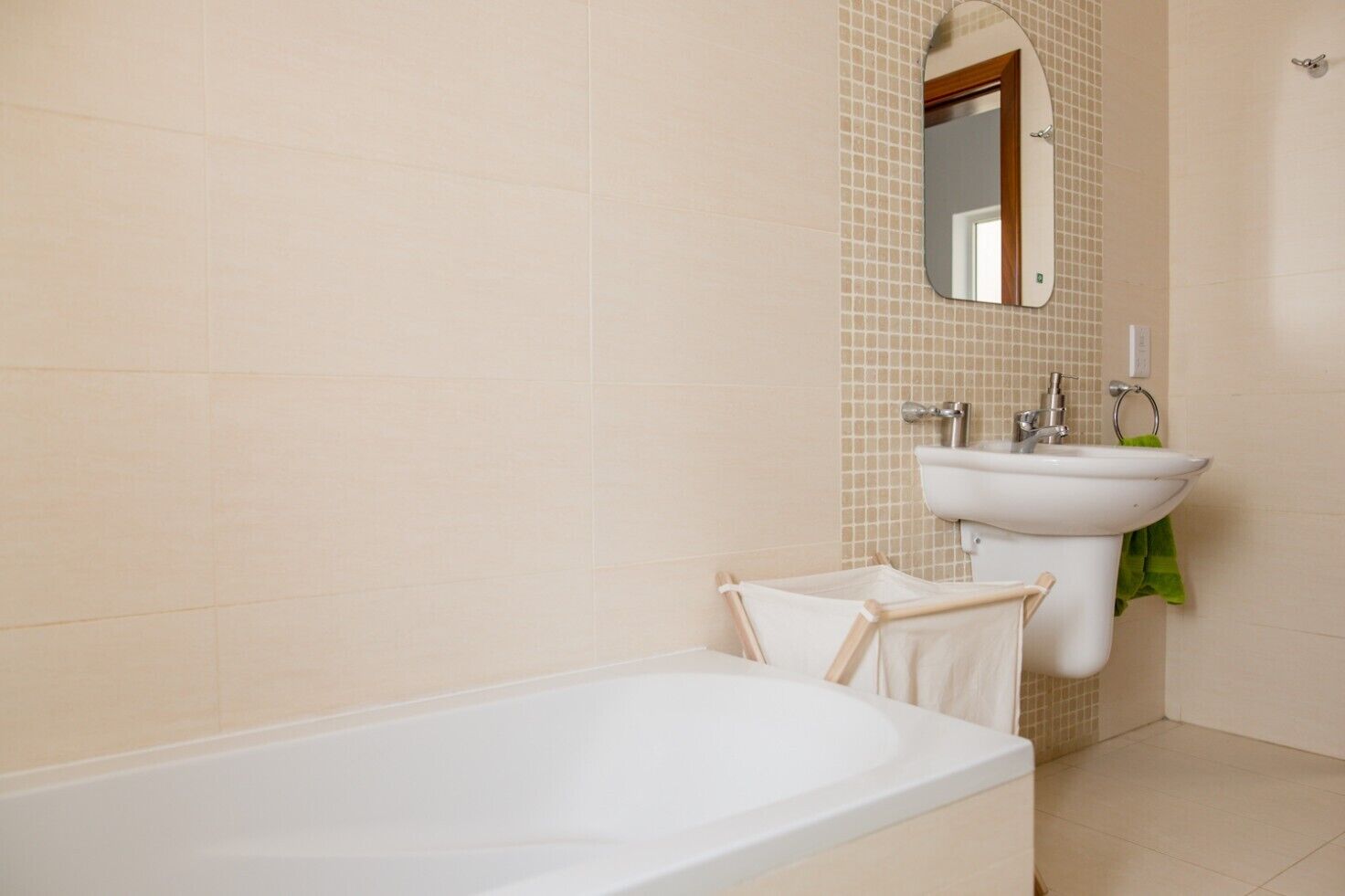 Ein Badezimmer mit einer weißen Badewanne, einem Waschbecken mit Spiegel und einem grünen Handtuch.