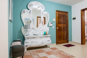 Una habitació amb un mirall gran, un armari, una cadira i una porta.