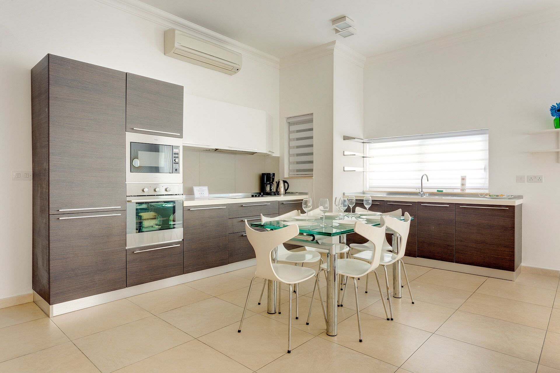 A modern kitchen with a dining area, featuring a built-in oven, microwave, and coffee maker.