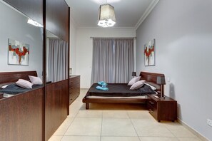 Une chambre à coucher avec un grand miroir, un lit avec des oreillers, une table de chevet et un luminaire suspendu.