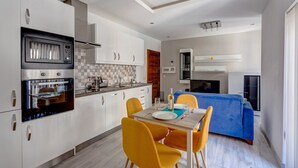 A compact kitchen with modern appliances, a dining area with yellow chairs, and a blue sofa in the living area. - Modern Apartment Just off the Promenade (Sliema)