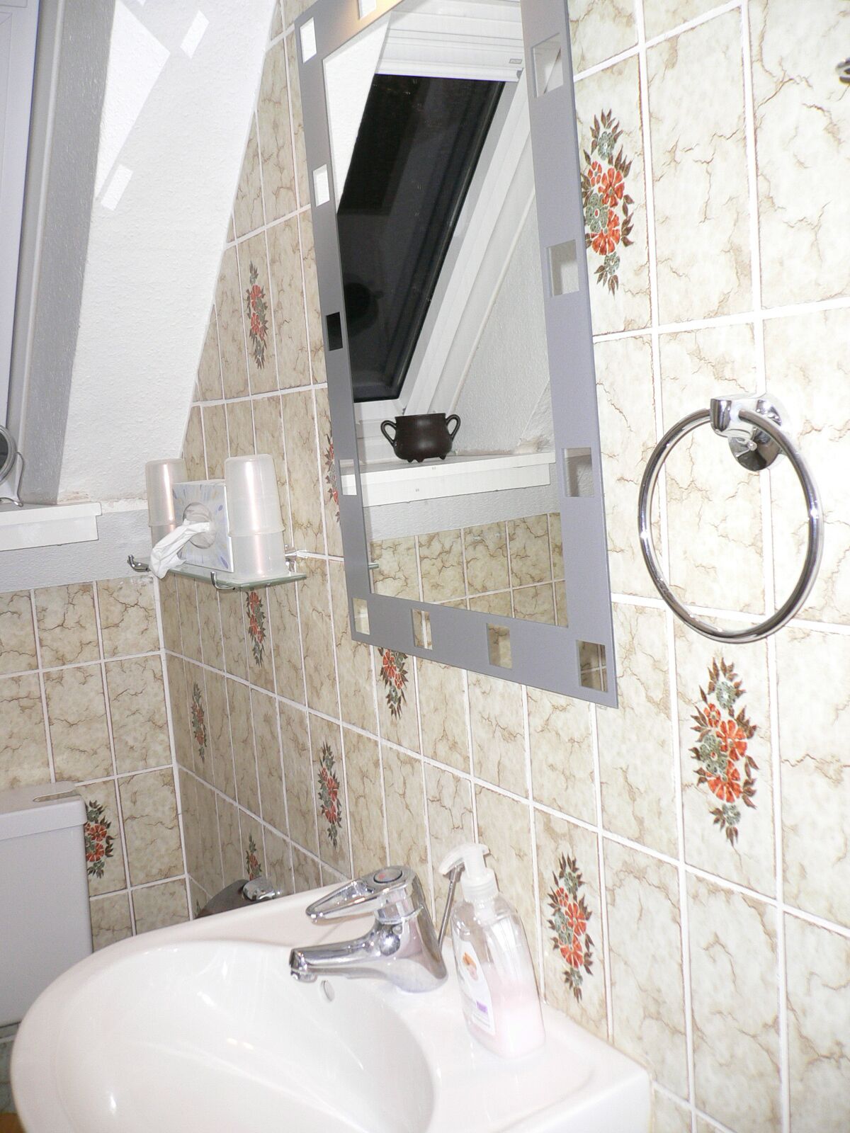 A bathroom with a sink, mirror, and decorative tiles.