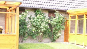 A house with a brick exterior, a tiled roof, and a wooden porch. - Holiday house with large garden, covered terrace, near the beach,  (Westerdeichstrich)