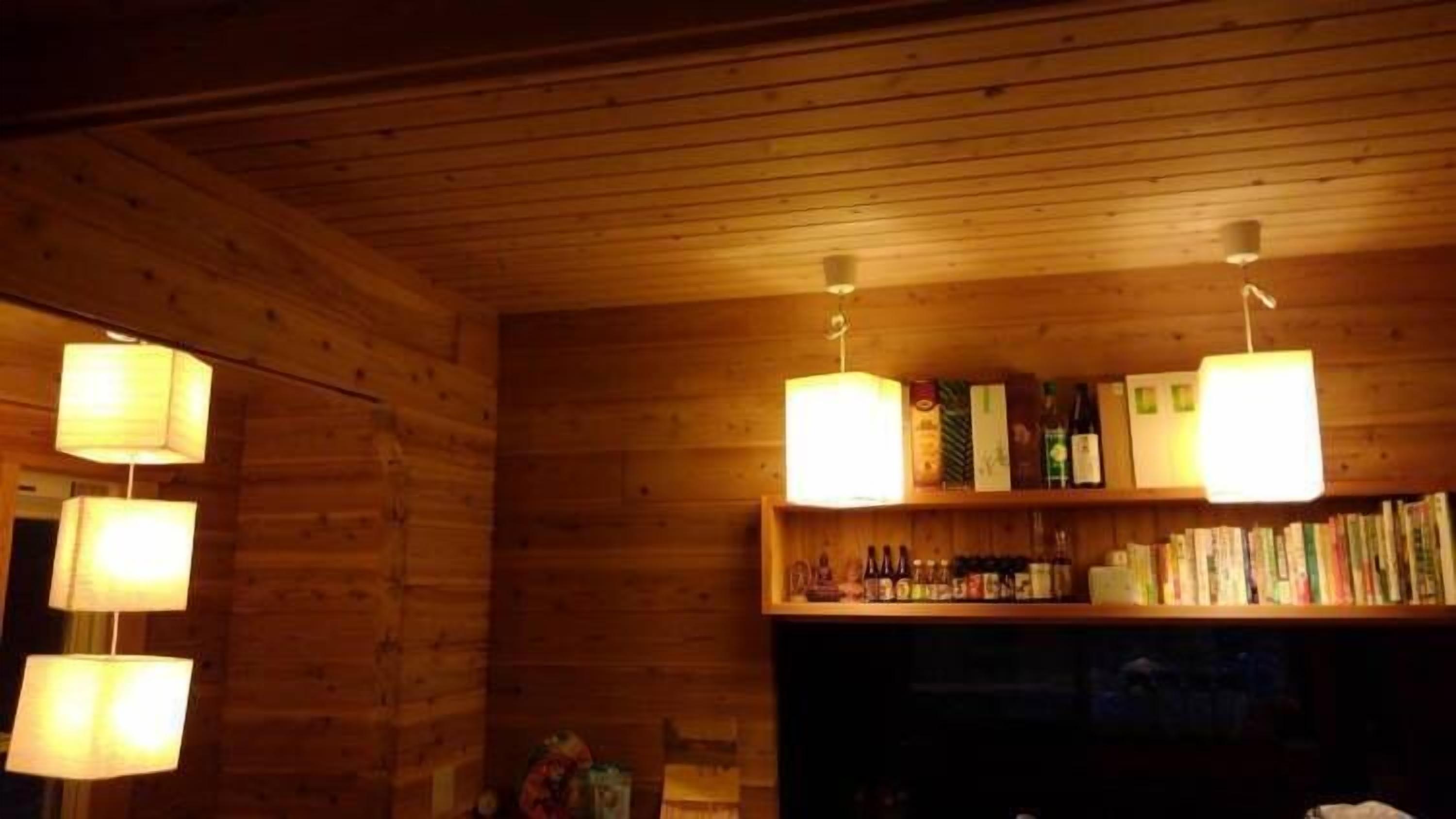 Un interior de madera con una estantería y lámparas colgantes.
