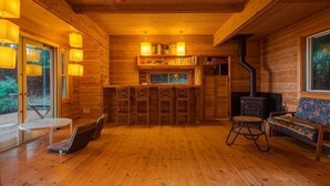 L’intérieur d’un chalet en bois comprend un bar, des sièges, une cheminée et une grande fenêtre.