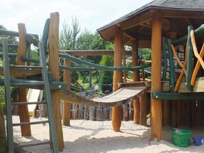 A wooden playground structure with climbing elements and a rope bridge. - Schneewittchenhütte- Holzblockbohlen Holiday house with fireplace and sauna in the Vogtland (Mühlental)