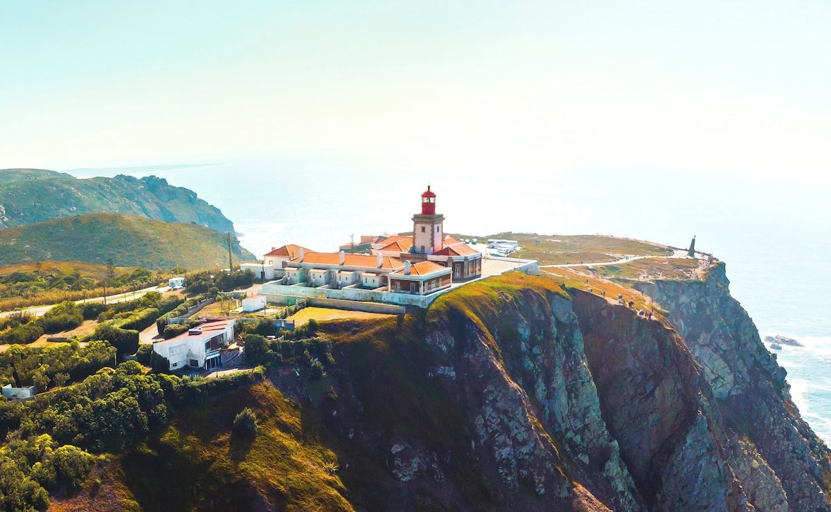 A coastal building with a lighthouse, situated on a cliff with ocean views.