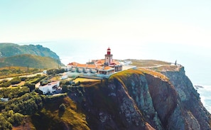 A coastal building with a lighthouse, situated on a cliff with ocean views.