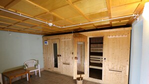 A room with wooden walls and a tiled floor, featuring a wooden table and a plastic chair. - Hotel Montriond (Val d'Illiez)