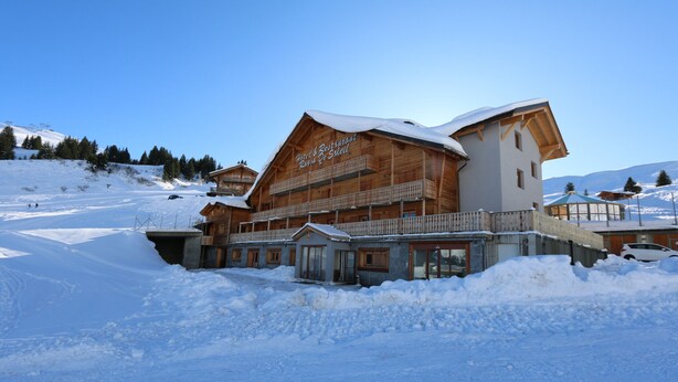 A large wooden building with a sign reading "Hotel & Restaurant Rion De Sheil" in a snowy landscape. - Hotel Montriond (Val d'Illiez)