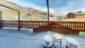 A terrace with a view of a mountainous area, wooden furniture, and a metal railing. - Hotel Montriond (Val d'Illiez)