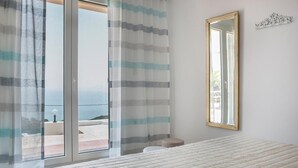A bedroom with a large bed, a window with curtains, and a mirror on the wall. - Countrystyle Villa Bonora (Skala Kefalonias)