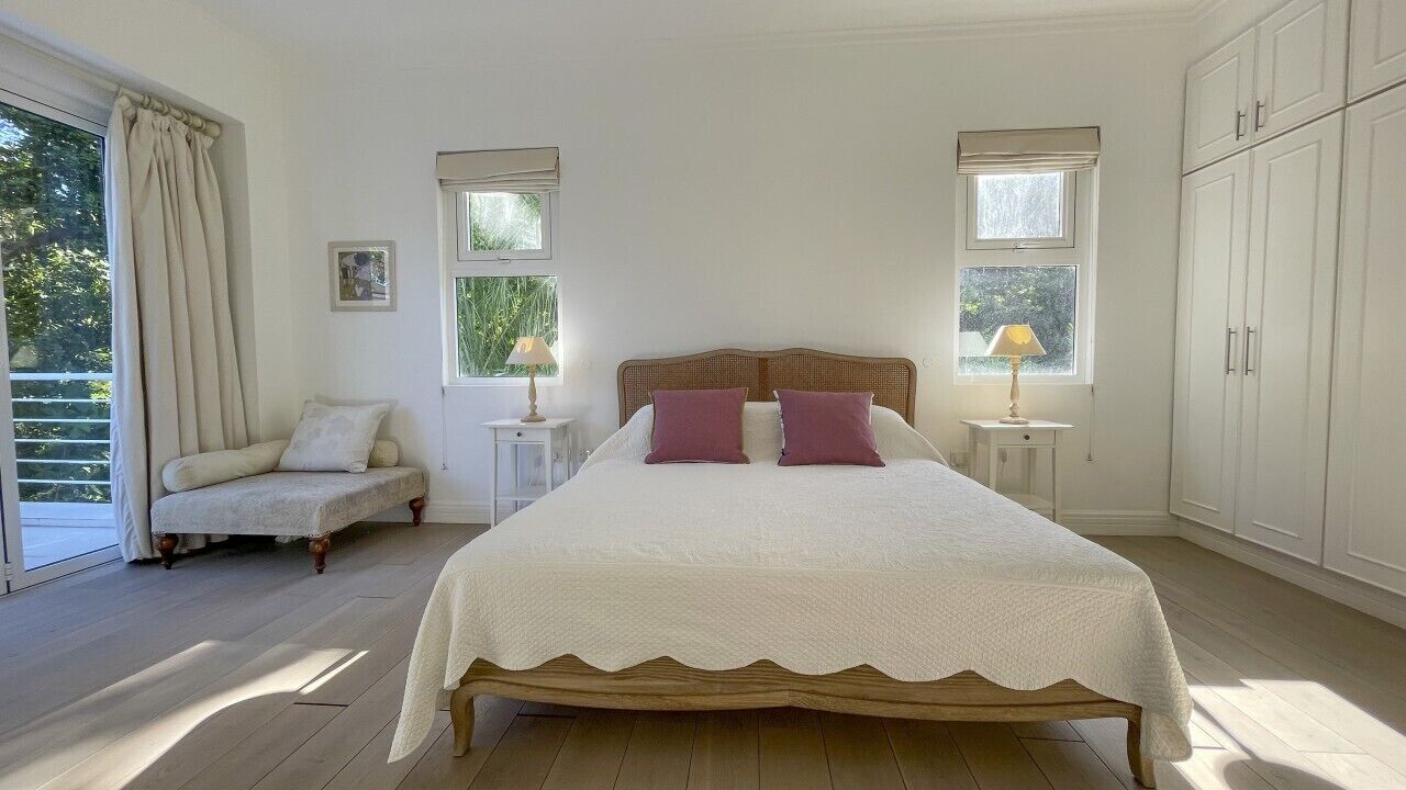 A bedroom with a large bed, two bedside tables, a chair, and a wardrobe.