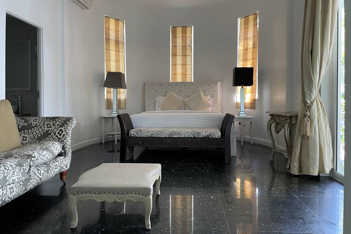 A bedroom with a bed, a sofa, a table, and a chair.