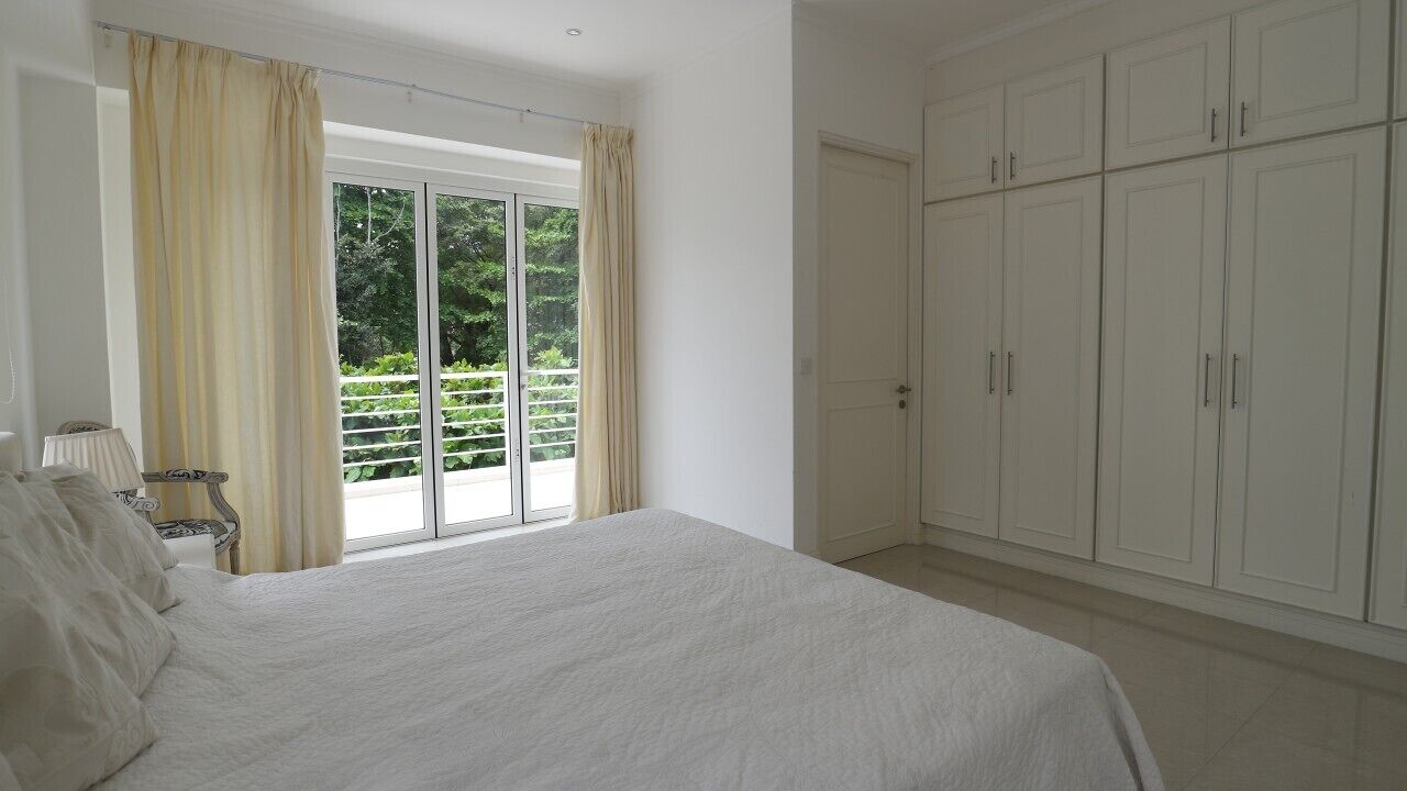 Una camera da letto con un letto grande, una porta scorrevole in vetro che dà su un balcone e armadi bianchi.