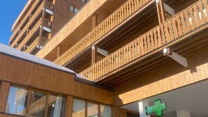 A building with a wooden facade, a pharmacy sign, and a green cross sign indicating a medical facility. - Spacious studio with wifi in Plagne Centre, near slopes (La Plagne)