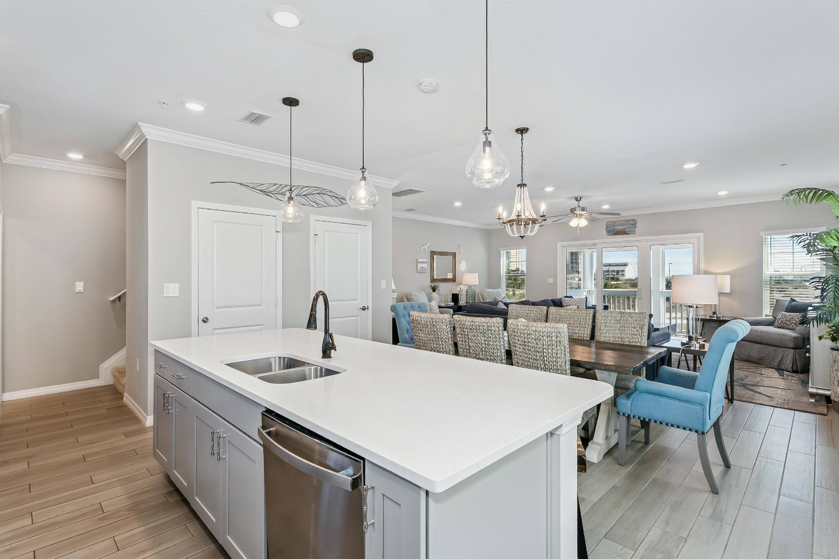A modern kitchen with a central island, stainless steel appliances, pendant lighting, and a dining area with a sofa and chairs.