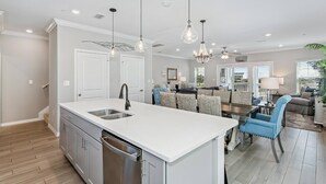 A modern kitchen with a central island, stainless steel appliances, pendant lighting, and a dining area with a sofa and chairs. - Monthly Rates Available | Footloose Lost Key Resort | Pet Friendly | Free Golf | Beach Club | Pools (Pensacola)