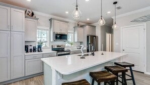A modern kitchen with white cabinetry, a large island with stools, stainless steel appliances, and pendant lighting. - Monthly Rates Available | Footloose Lost Key Resort | Pet Friendly | Free Golf | Beach Club | Pools (Pensacola)