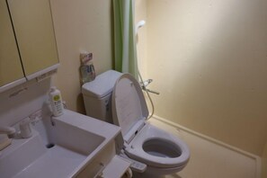 A bathroom with a white sink, toilet, and a bottle of hand soap on the counter. - Sasayakanayado Futtsu (Futtsu)