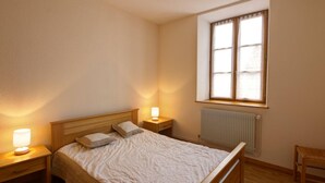 Een slaapkamer met een enkel bed, twee bedlampjes, een raam met uitzicht en een radiator.