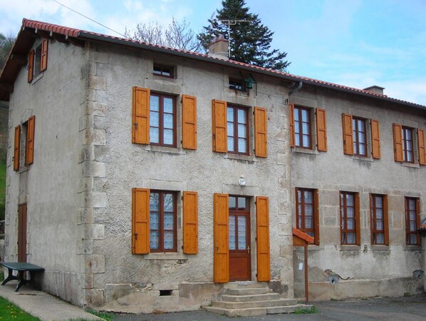 A two-story building with a stone facade and wooden shutters on the windows.