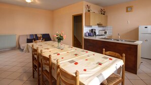 Una cocina compacta con comedor, que incluye una mesa preparada para cuatro personas, un refrigerador y un microondas.