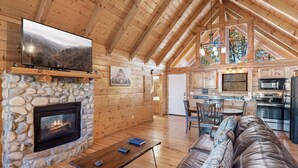 A cozy cabin interior with a stone fireplace, wooden walls, a leather sofa, and a kitchen area. - Moonlight Obsession, a Secluded Dog-Friendly Cabin located just minutes from downtown Gatlinburg (Gatlinburg)