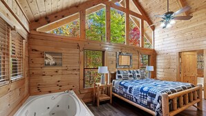 A log cabin bedroom with a large wooden bed, a wooden bench, a bathtub, and a ceiling fan. - Moonlight Obsession, a Secluded Dog-Friendly Cabin located just minutes from downtown Gatlinburg (Gatlinburg)