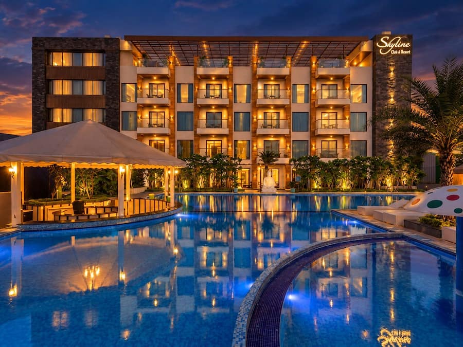 Un hotel con piscina, asientos al aire libre y un letrero que dice 'Skyline Club & Resort'.