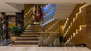 A modern hotel lobby with marble flooring, a staircase with illuminated steps, and a large potted plant. - Skyline Resort & Convention Centre (Indore)