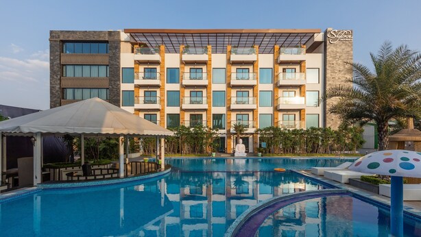 A hotel with a swimming pool, outdoor seating, and a modern building facade. - Skyline Resort & Convention Centre (Indore)