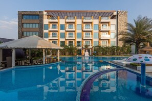 A hotel with a swimming pool, outdoor seating, and a modern building facade. - Skyline Resort & Convention Centre (Indore)