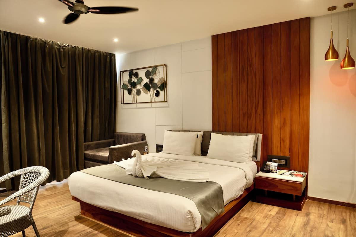 A hotel room with a bed, a chair, a nightstand, and a ceiling fan.