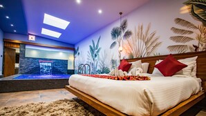 A modern bedroom with a wooden bed, a large wall mural of tropical plants, and a small indoor water feature. - Skyline Resort & Convention Centre (Indore)