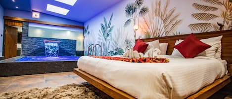 Un dormitorio moderno con una cama de madera, un gran mural de plantas tropicales y una pequeña fuente de agua interior.