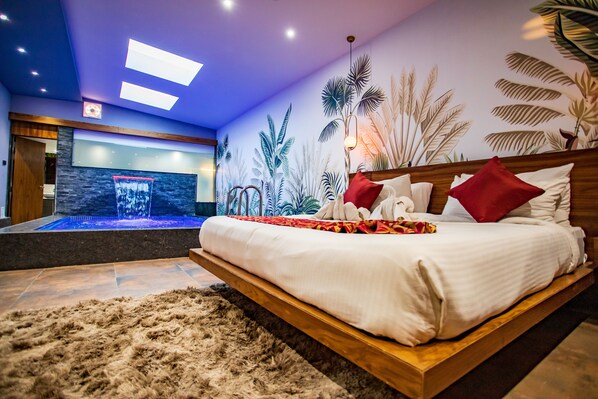 A modern bedroom with a wooden bed, a large wall mural of tropical plants, and a small indoor water feature. - Skyline Resort & Convention Centre (Indore)