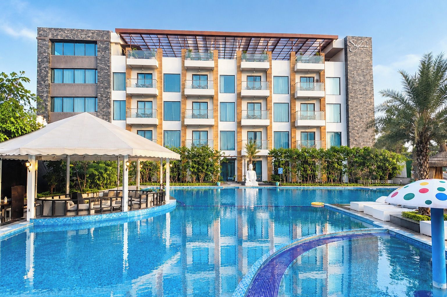 A hotel with a swimming pool, outdoor seating, and a modern building facade.