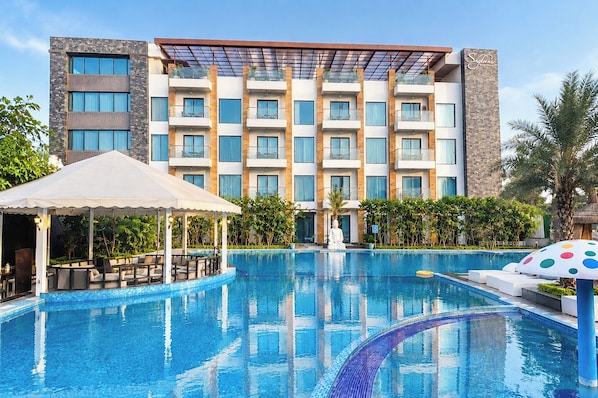 Un hotel con piscina, mobiliario exterior y fachada de edificio moderna.