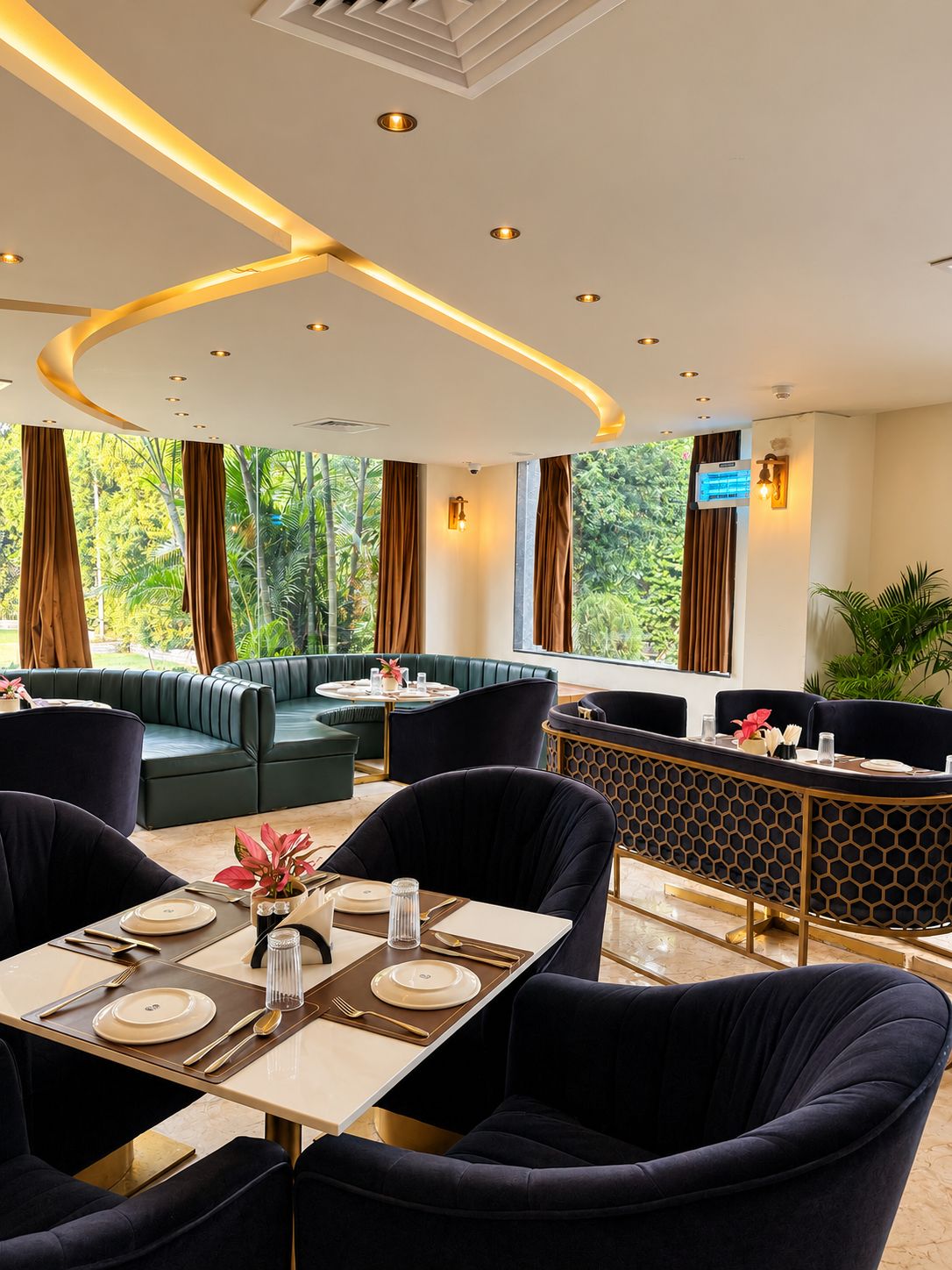 A restaurant with a modern interior, featuring a dining area with tables and chairs, a bar area, and large windows offering a view of greenery outside.