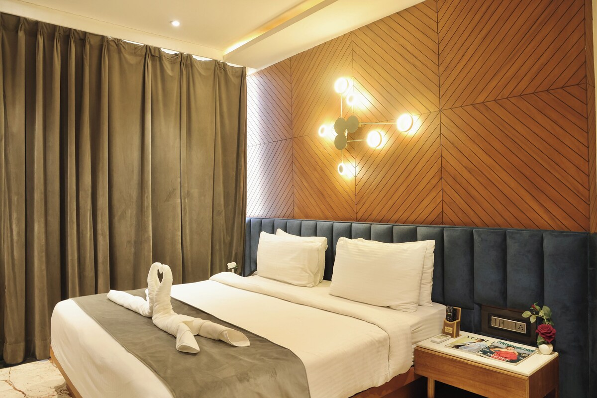 A hotel room with a neatly made bed, a bedside table with a remote control, a magazine, and a decorative item.