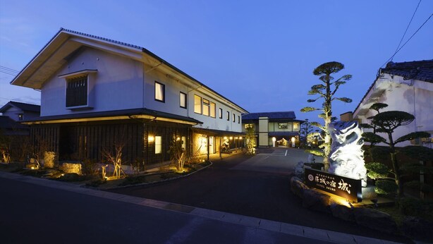 Ein traditionelles japanisches Hotel mit zweistöckiger Bauweise, einem gut beleuchteten Eingang und einer Steinhlaterne.