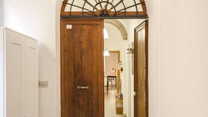A hallway with a wooden door, white walls, and a tiled floor. - Appartamento Schiavonia (Bologna)