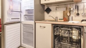 A compact kitchen with a refrigerator, a dishwasher, and a sink. - Appartamento Schiavonia (Bologna)