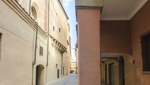 A narrow alleyway with buildings on either side, featuring arched doorways and a clear sky above. - Ca' di Leo (Bologna)