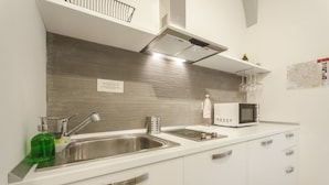 A modern kitchen with a stainless steel sink, a microwave, and a white countertop. - Le Torri Suite (Bologna)