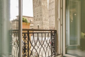 Un balcon doté d’une balustrade en fer forgé, offrant une vue sur un bâtiment historique surmonté d’une haute tour.
