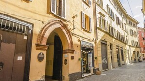 En historisk byggnad med en framträdande portal som huvudentré, en butik på bottenvåningen och en kullerstensgata.